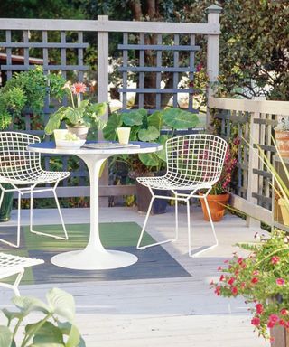 Outdoor decking with white table and chair set and rectangular painted motif in blue and green on deck