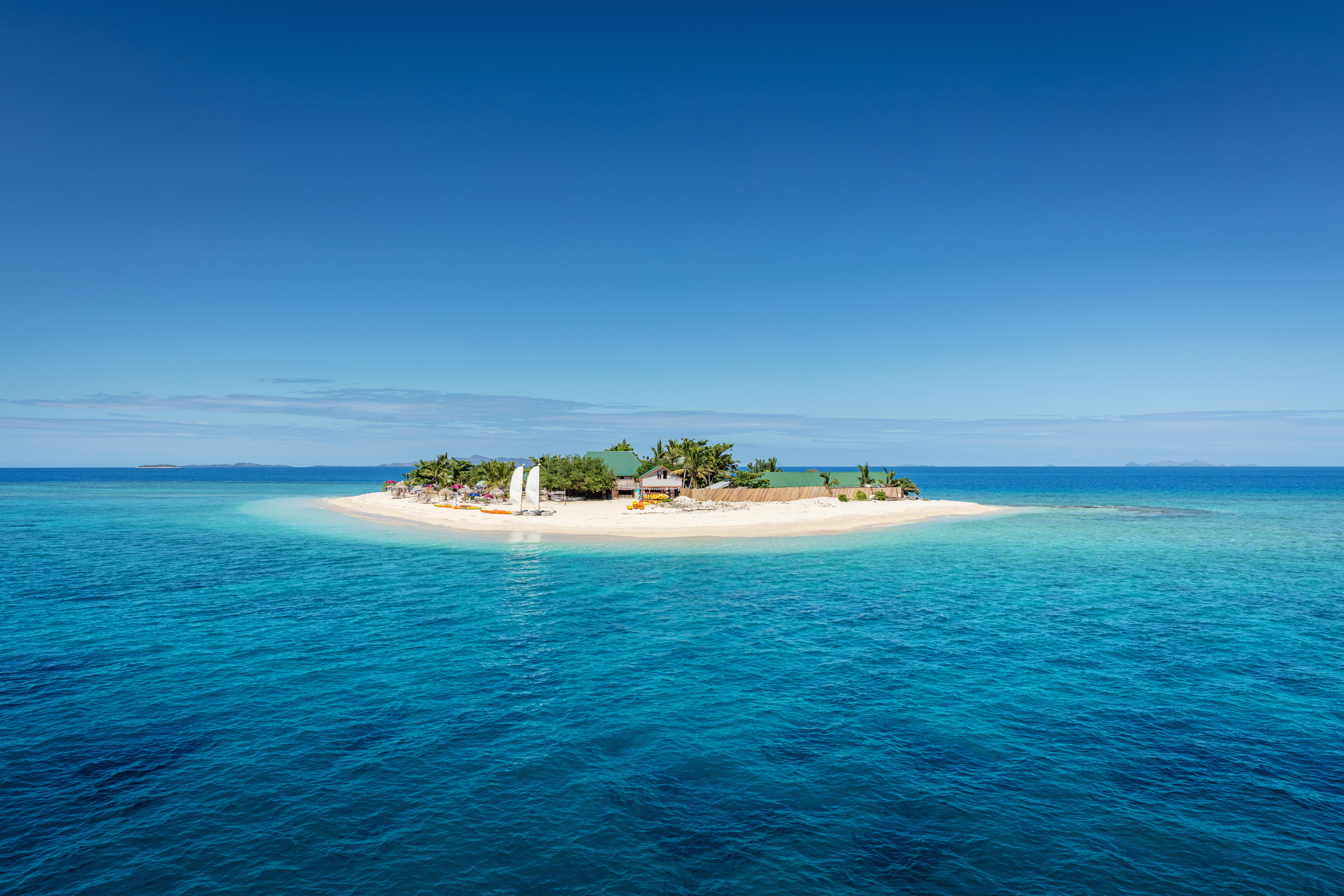 Fiji Mamanuca Islands Beautiful Small Islet in the middle of the south pacific ocean with beach huts, lounge chairs, palm trees, surrounded with beautiful clear turquoise water. Islet, Mamanuca Islands, Fiji, Melanesia