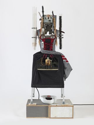 View of Heidi, 2018, by Tom Sachs - a hot drinks machine styled to look like a woman with two blonde plaits and a black and white checked dress with red elements
