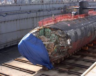Dry dock reveals the damage from the underwater collision of a USS San Francisco submarine with an uncharted seamount. Some 23 seamen were injured, one fatally. The submarine was almost lost.