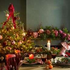 A dining room with a Christmas tree beside a dining table set for Christmas dinner 