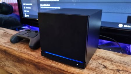 A Steam Machine in front of a TV, with the Steam Controller next to it