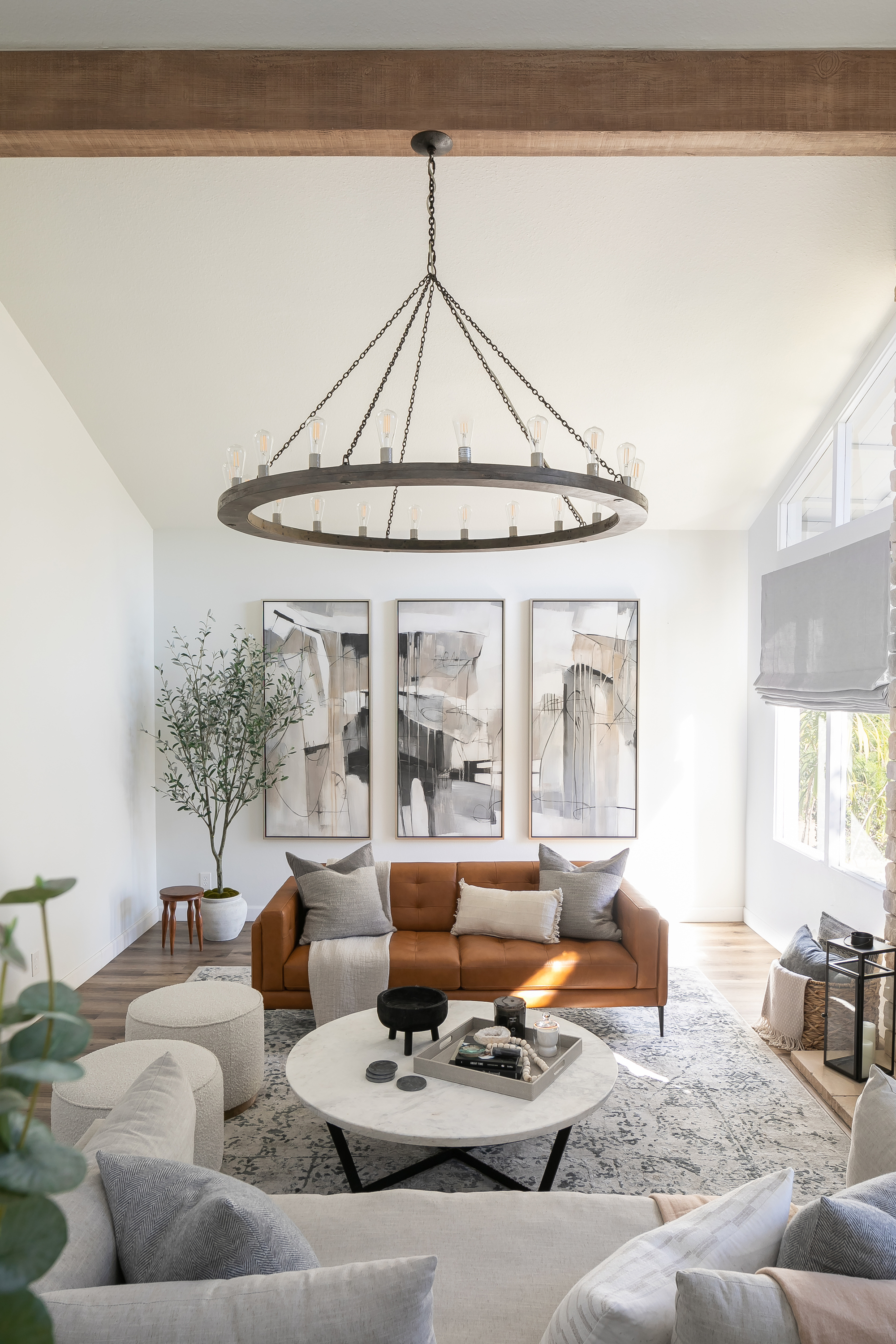 A living room with white decor, a leather sofa, and a circular chandelier light hanging from the ceiling