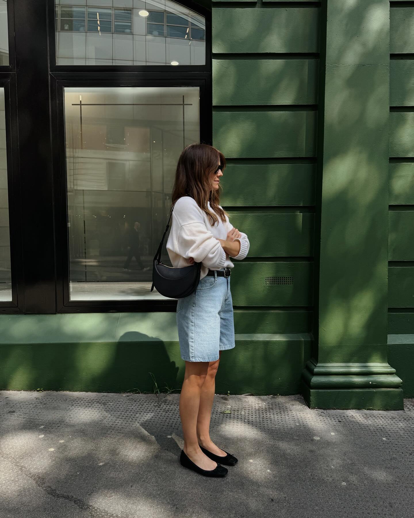 Influencer wears denim shorts and ballet flats.