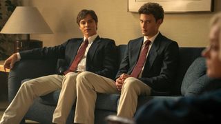 Erik (Cooper Koch) and Lyle (Nicholas Chavez) sitting next to one another on the sofa in "Monsters: The Lyle and Erik Menendez Story" on Netflix