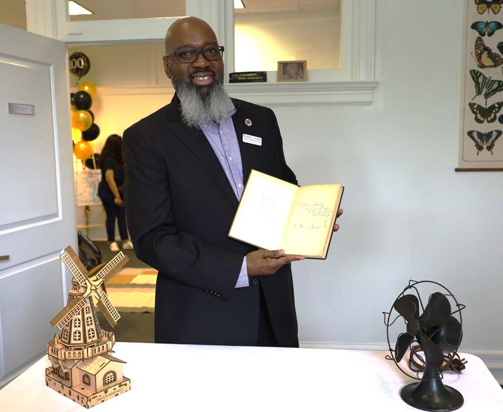 Renard Jenkins, immediate past president of SMPTE, poses with an autographed copy of C. Francis Jenkins’s autobiography and replicas of the toy windmill and electric fan used in the 1925 demonstration.