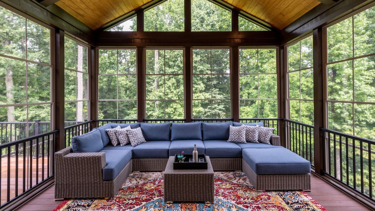 New modern screened porch with patio furniture, summertime woods in the background. New home addition concept.