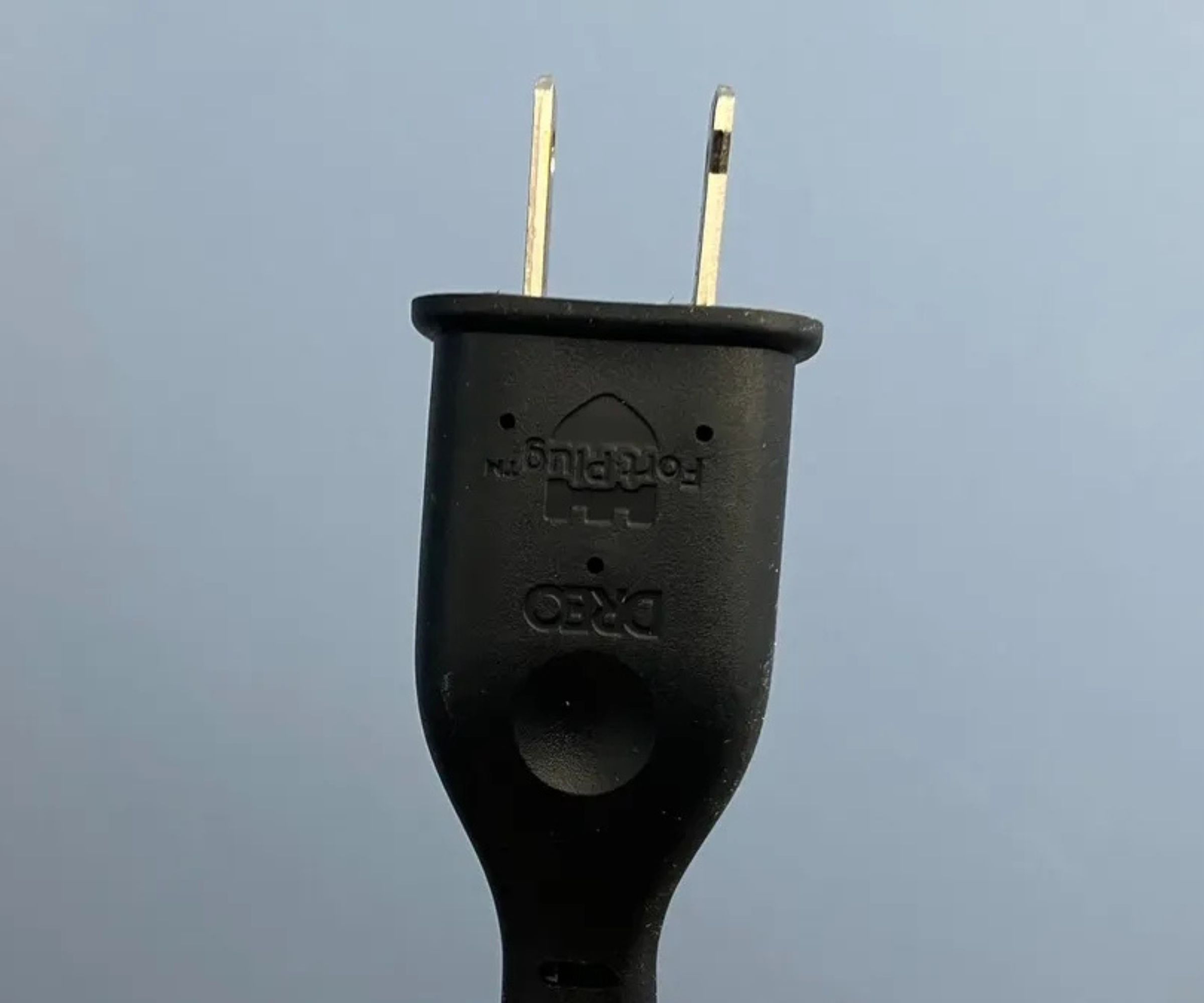 Photograph of the Dreo 2-in-1 Tower Fan and Heater MC706's black, US power plug against blue wall.