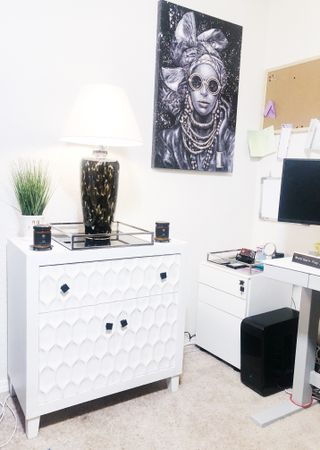 An organised office space with white sideboard with honeycomb pattern on doors