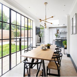 pendant light above wooden dining room table with critall windows, white walls and wooden floors
