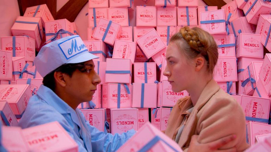 A still from The Grand Budapest Hotel in which main characters Zero Moustafa and Agatha are surrounded by pink cake boxes.