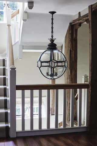 Staircase with large glass pendant light above seen from landing