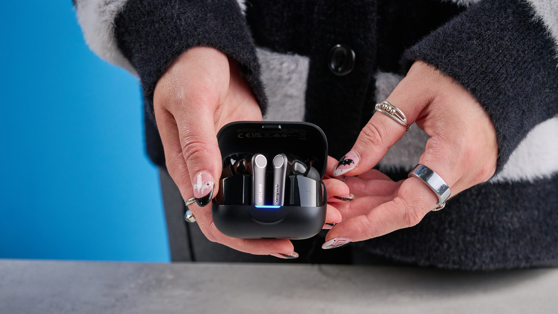 the earfun air pro 4+ earbuds in black showing the ear tips, charging case, and being worn