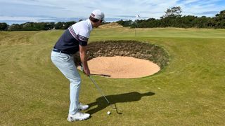 A golfer preparing to hit a shot over a bunker