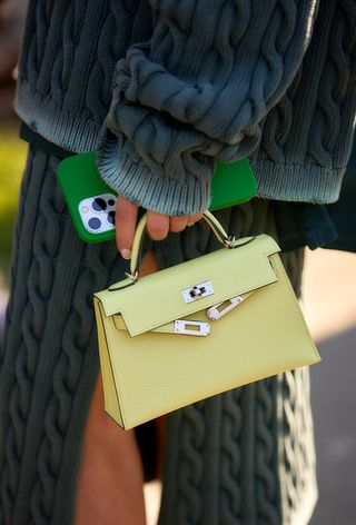 a street-style photo of a woman carrying a Hermés bag in a story about how to buy an hermés bag