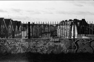Graffiti on a wall with houses behind it taken on Ilford HP5 Plus 35mm film