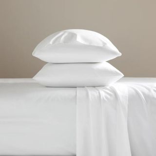 Brooklinen Classic Percale Core Sheet Set on a bed against a beige wall.