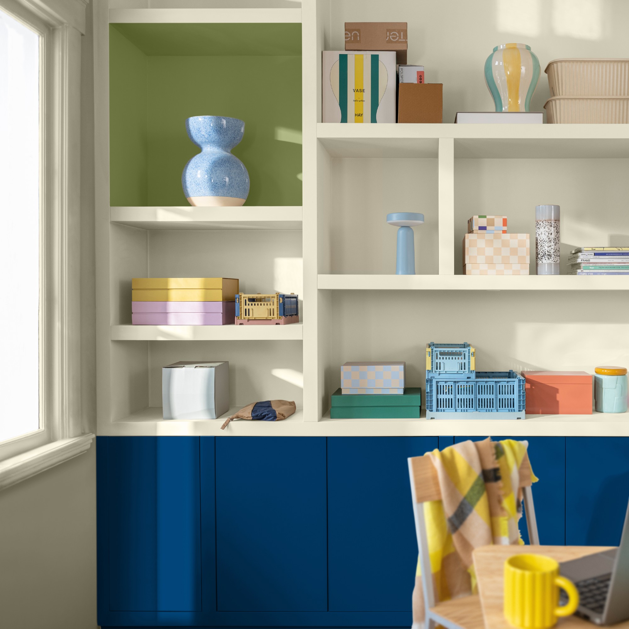Dulux&#039;s Free Groove blue paint used on storage cabinets below open shelving displaying colourful decorative objects