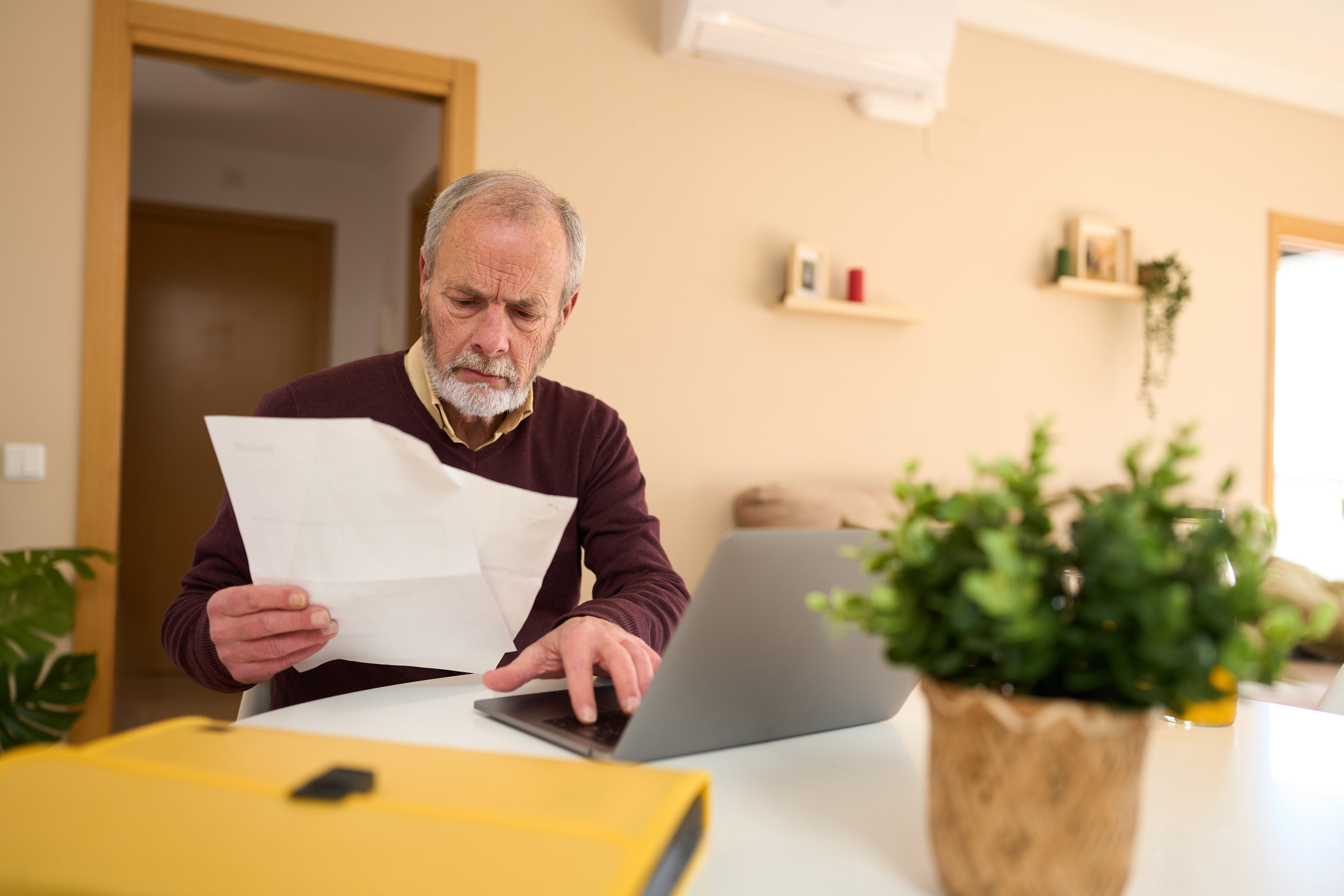 A man reviewing his personal finance with laptop and documents at home