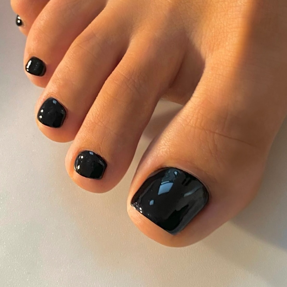 A close-up of a glossy black pedicure