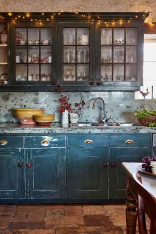 Blue shaker style kitchen with glass front cabinets and marble work tops