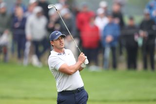 Koepka strikes an iron shot and watches its flight
