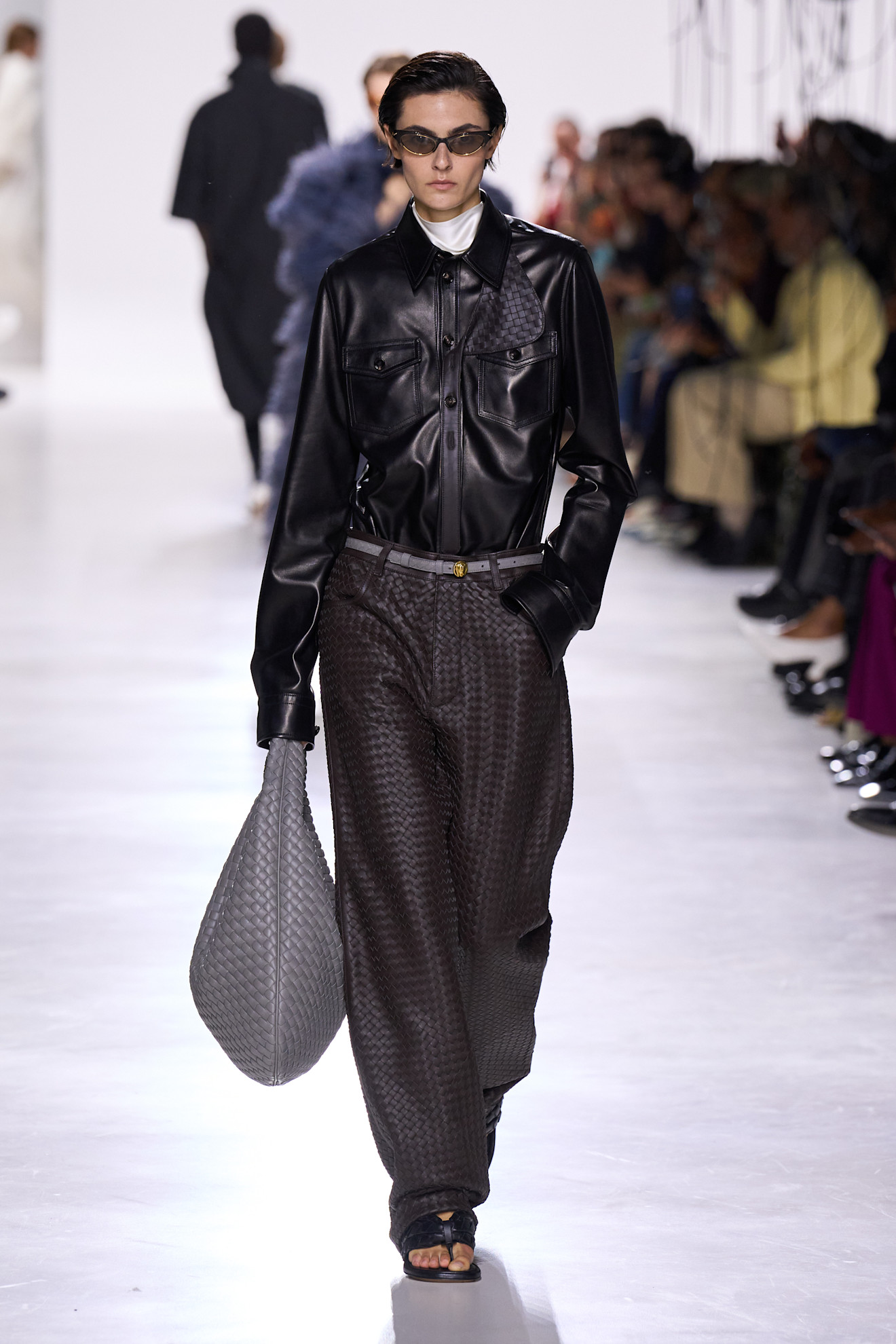Model on Bottega Veneta S/S26 runway wears leather shirt, leather trousers, carries Veneta bag