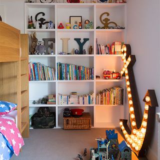 childrens room with white wall and shelf on wall with books