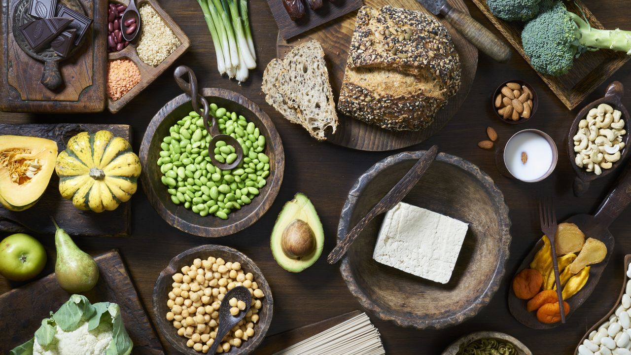 wooden table with avocado, tofu and more vegan food