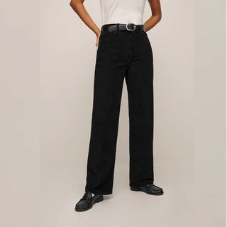 Reformation model wearing black corduroy pants and loafers