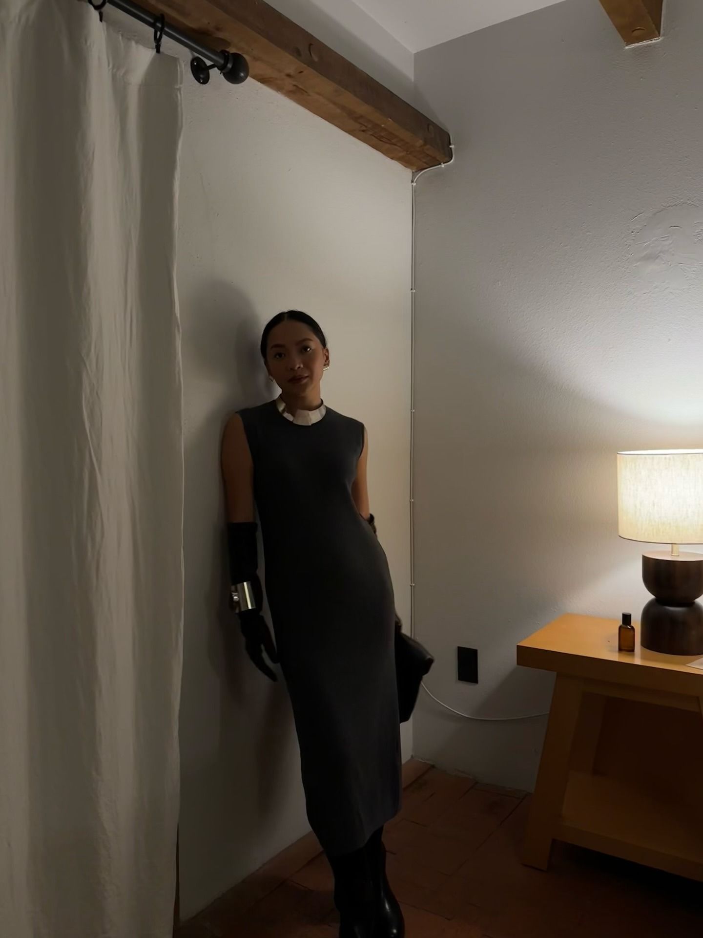 Dawn wears a gray sweater dress with black gloves and a silver necklace.