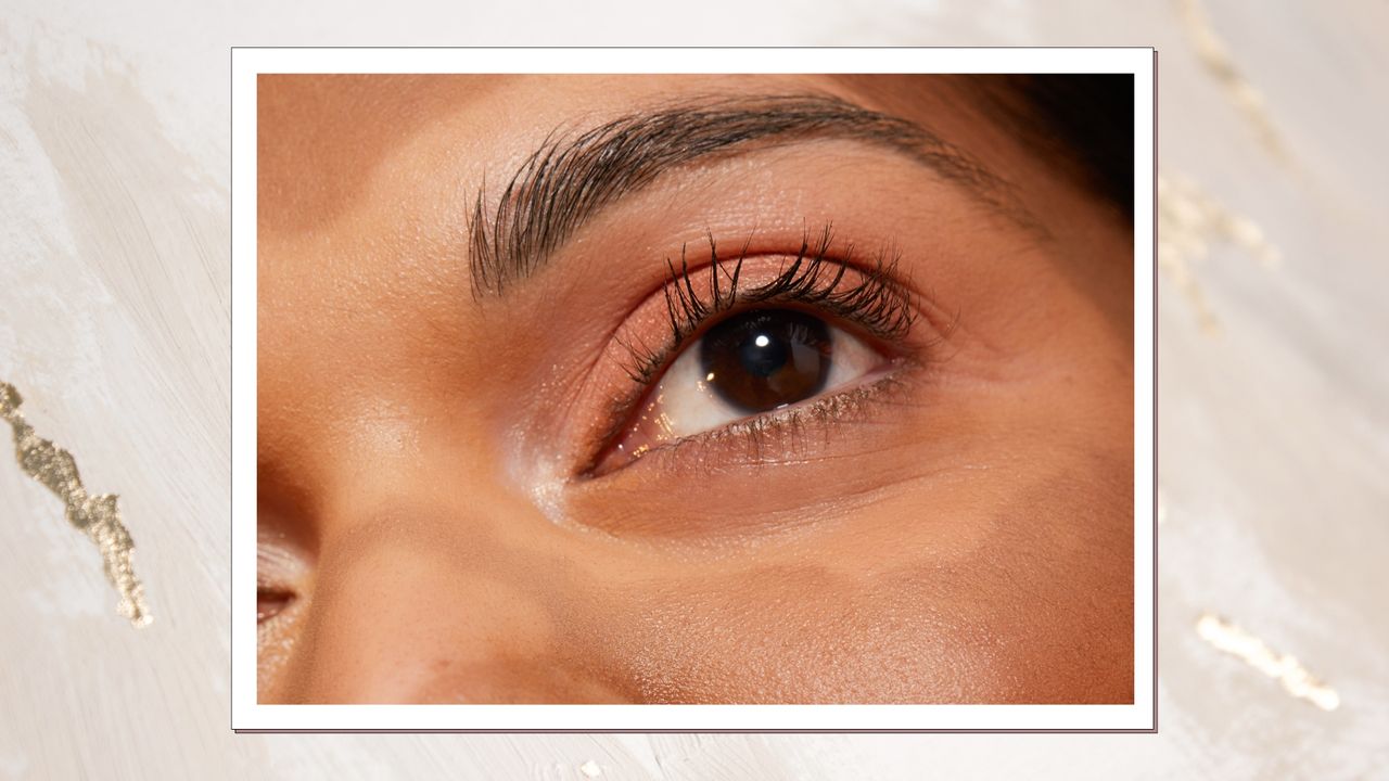 A close up of a woman&#039;s eye and eyelashes - which are long and fanned out/ in a gold foil and cream Christmassy template