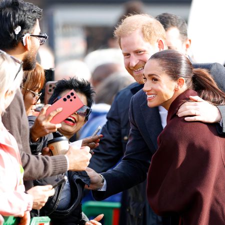 Prince Harry meeting fans with his arm around Meghan