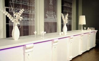 A brasserie-style white 'long bar' constructed from paper stock.