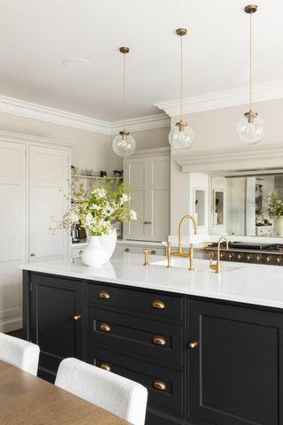 Image of a white kitchen with an island that is painted in a dark gray/blue paint color.