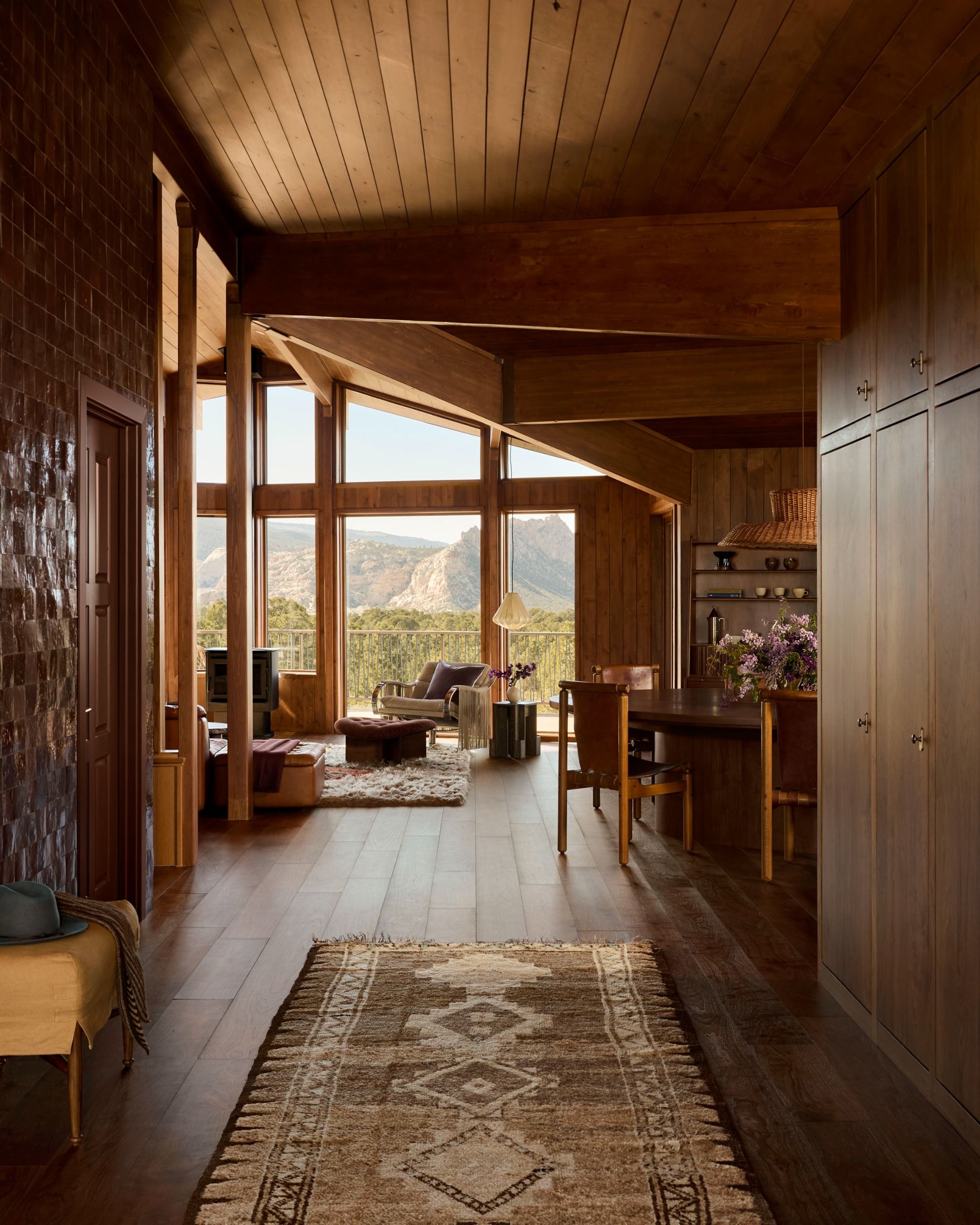 A transitional space with a patterned rug, and clad all over in wood paneling with views at the far end of the Utah desert