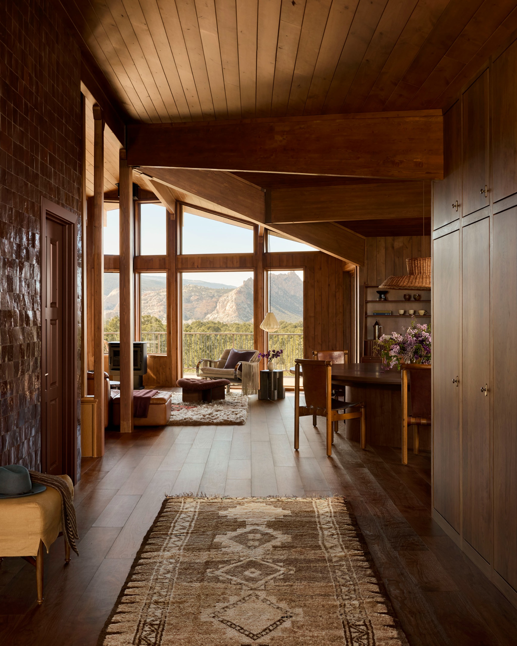 A transitional space with a patterned rug, and clad all over in wood paneling with views at the far end of the Utah desert