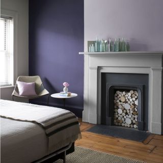 bedroom with alcove, fireplace with mantelpiece above it and wooden flooring, with lilac and lavender walls