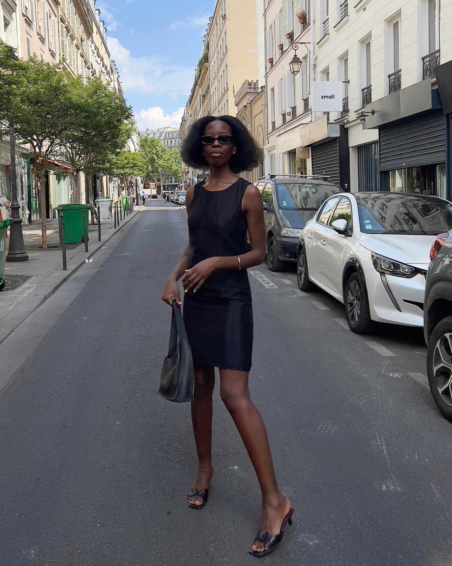 A woman in Paris wearing a black mini dress with a blunt bob hairstyle
