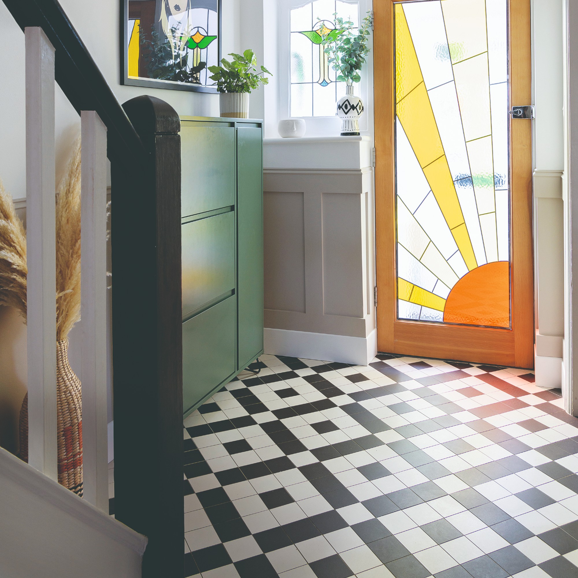 A hallway with a tiled patterned floor and glass front door