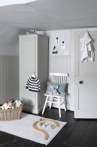 gray and white playroom/kids room with wardrobe, shiplap, chair, rug, basket of toys