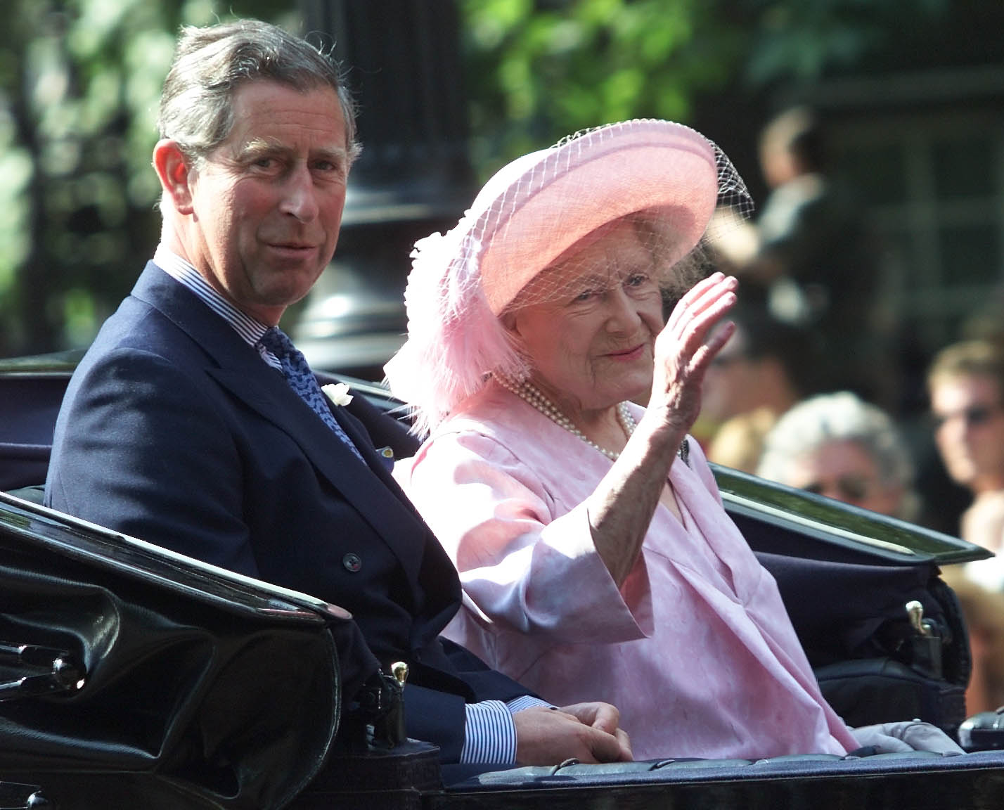 The Queen Mother waving in a carriage next to King Charles