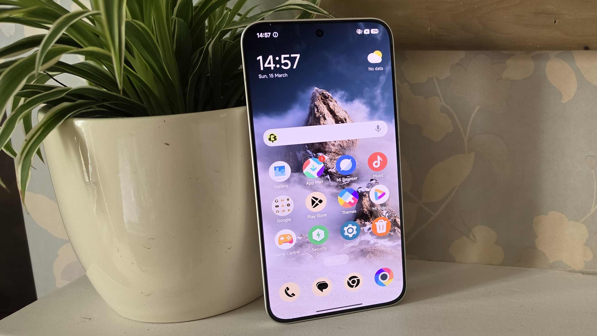 The Poco X8 Pro Max's home screen, while the phone is leaning on a plant pot.