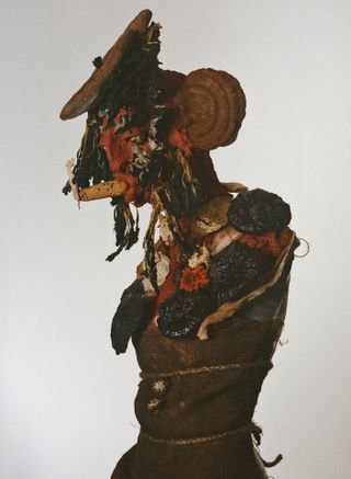 White background, red Mexican clay head, half mannequin sculpture, with mushrooms, corn and dark brown antique fabric