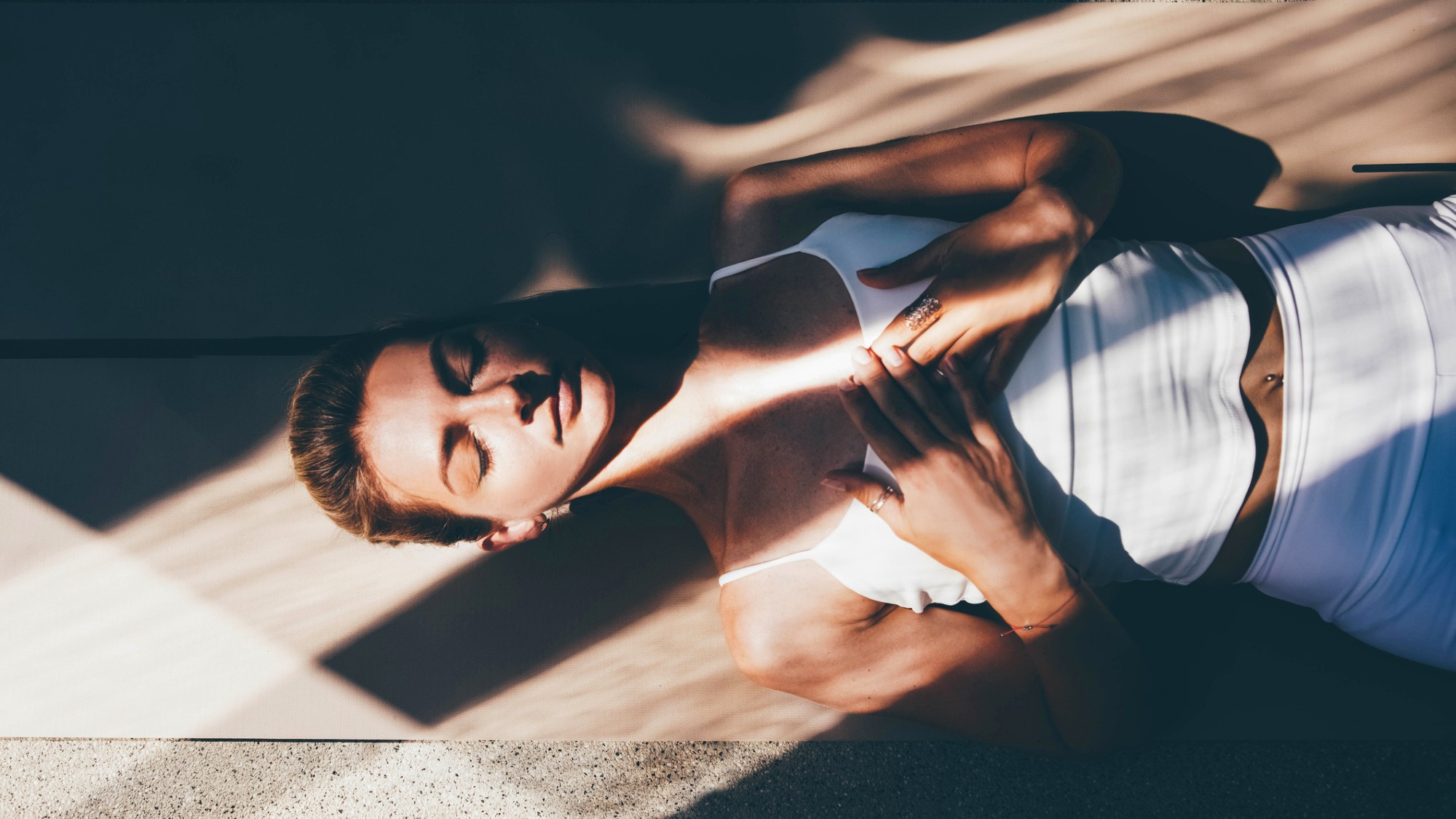 A woman relaxes in a meditative pose on a yoga mat.