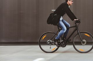 Commuter rides to work on a flat bar hybrid bike with disc brakes