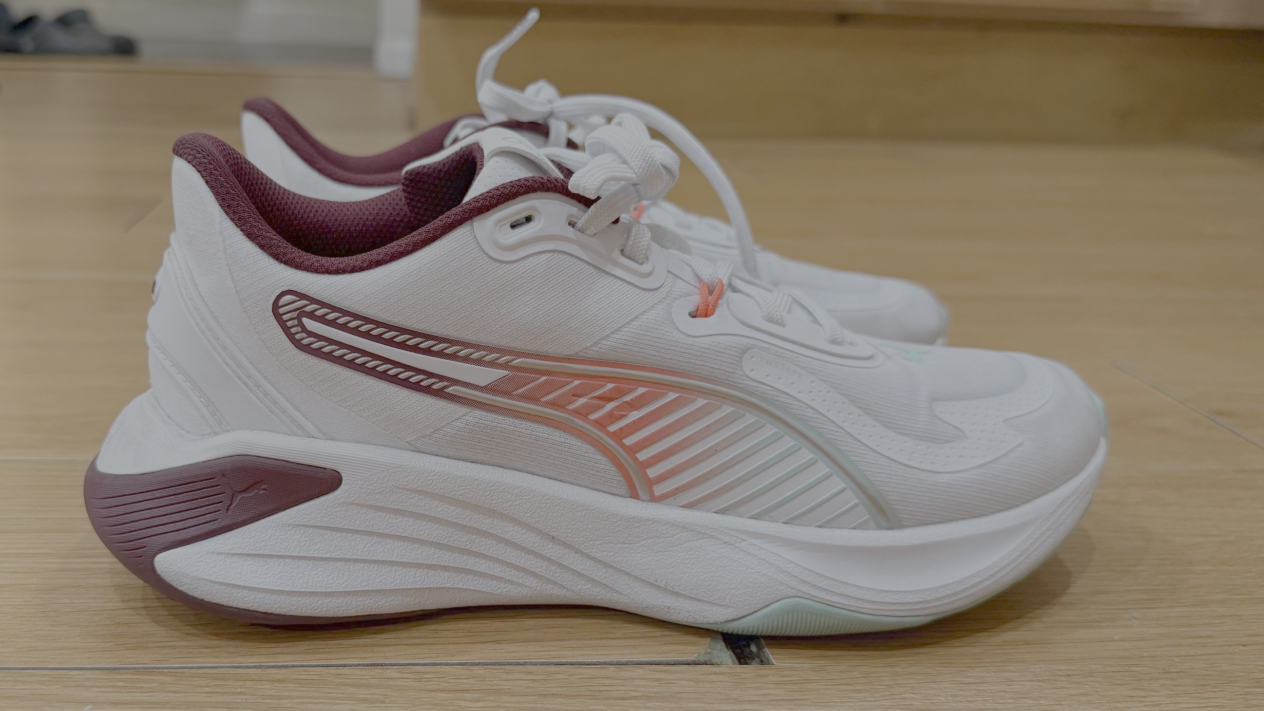 A pair of white puma pwr hybrid shoes on a wooden floor