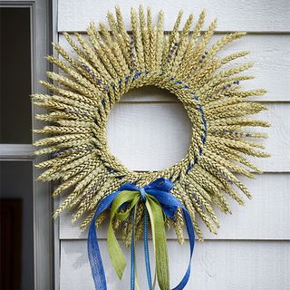 corn wreath with blue green ribbon on white wall
