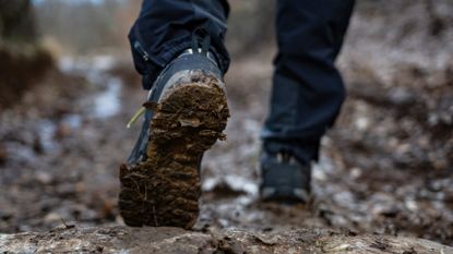 A pair of hiking boots walking through the mud