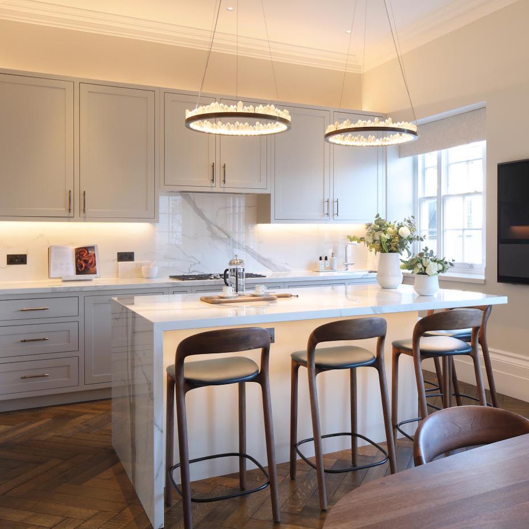 kitchen with white cabinets and island with three bar stools and wood flooring
